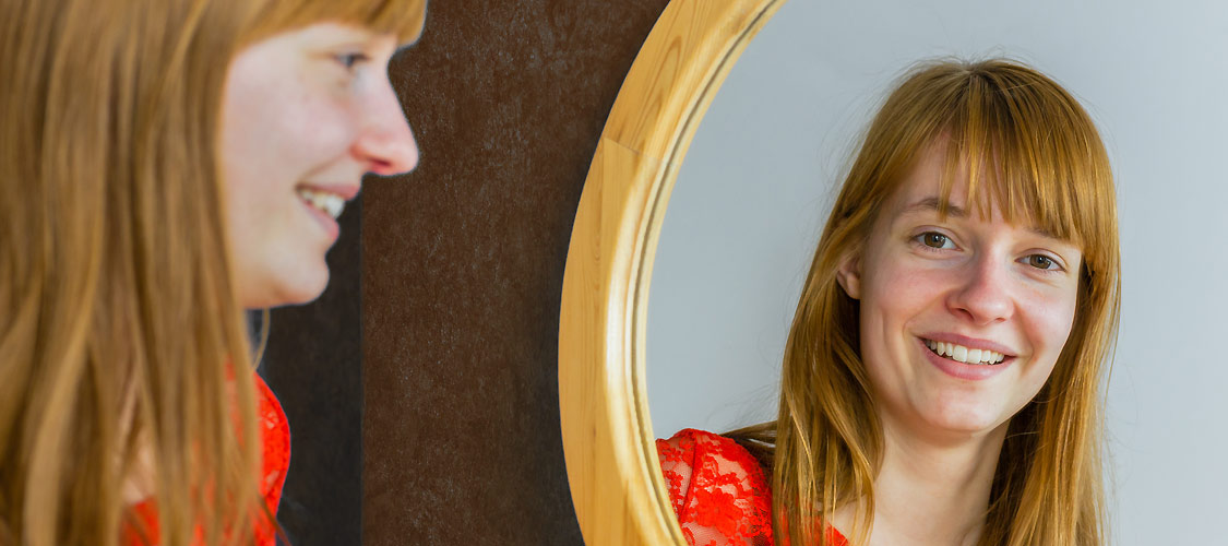 ein hübsches junges Mädchen schaut in einen Spiegel